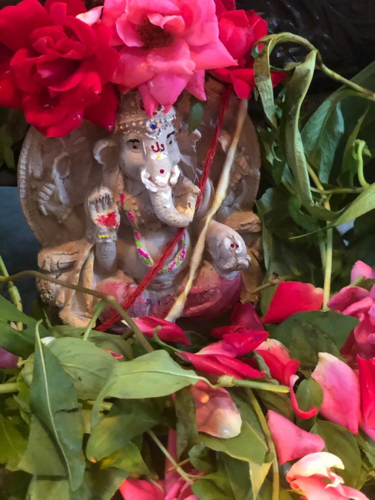 A real hand-decorated clay Ganesha moorthi surrounded by roses